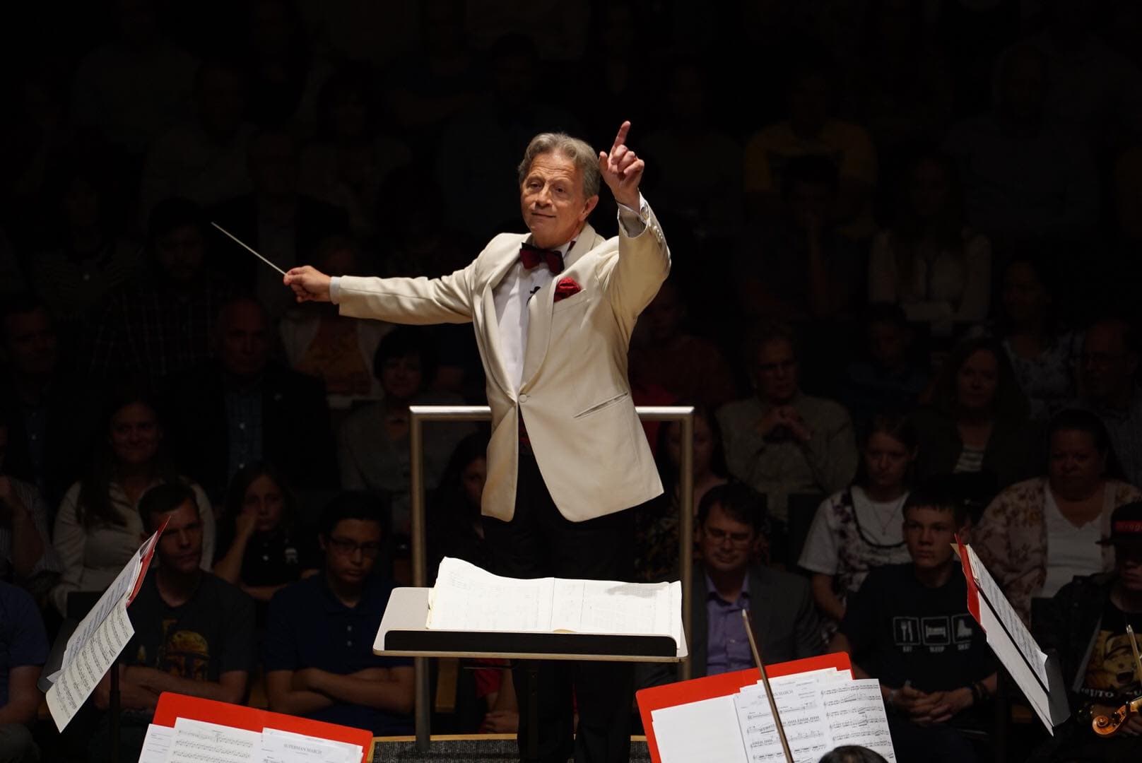 Conductor in white jacket conducting an orchestra